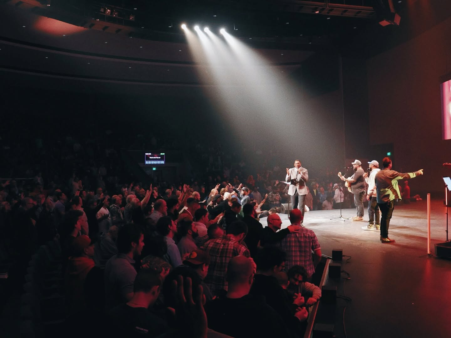 Men gathered near the stage during worship at Invincible 2026
